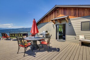 A deck with a table and chairs, a grill, and a view of mountains.