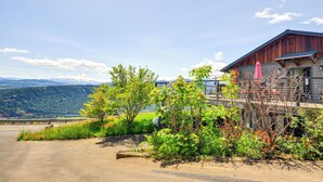 A building with a wooden exterior and a balcony with a pink umbrella. - Mt Hood Views: Modern Underwood Home w/ Deck! (Underwood)