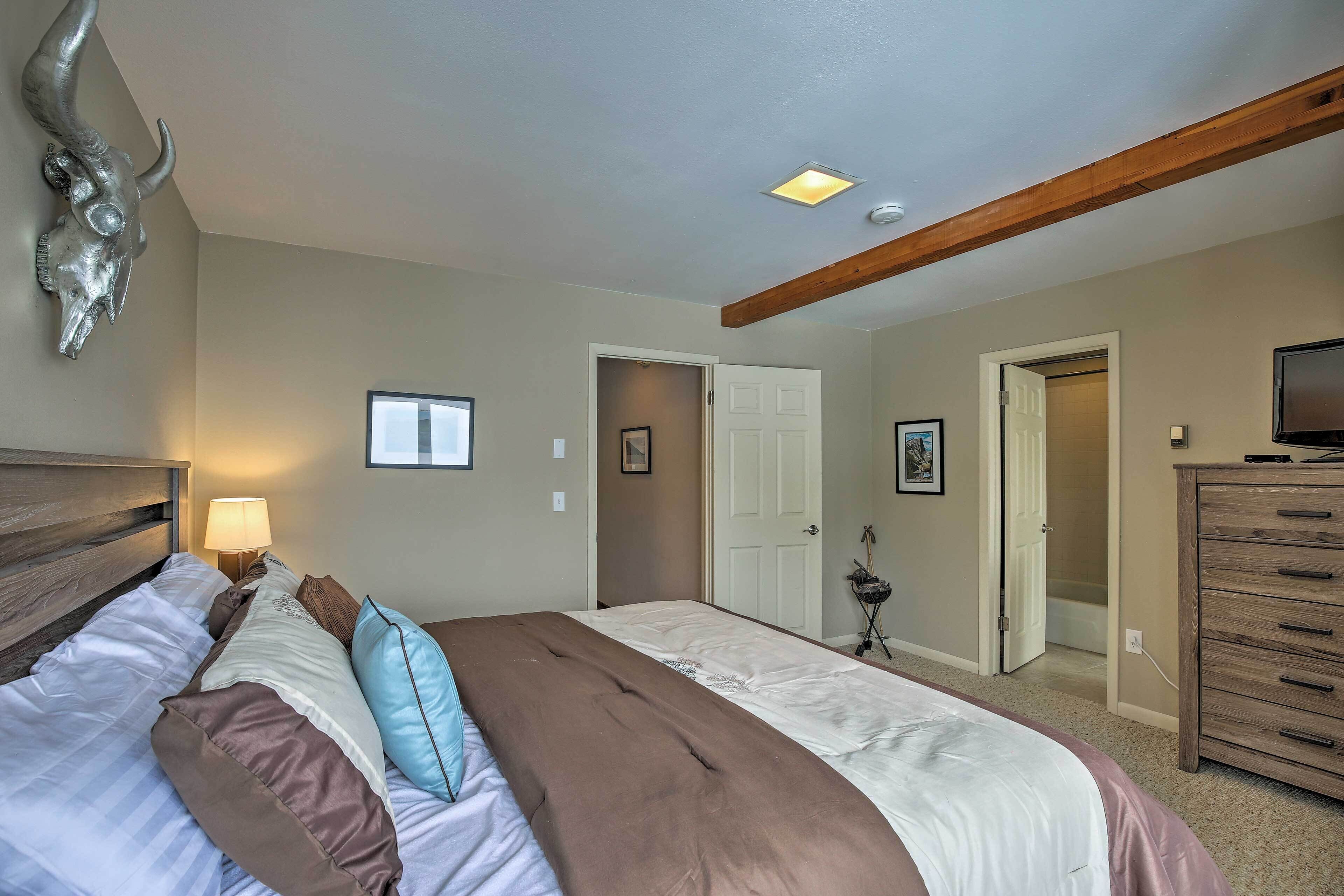 Un dormitorio con cama, lámpara de noche, cabecera de madera y una decoración de cráneo colgado.
