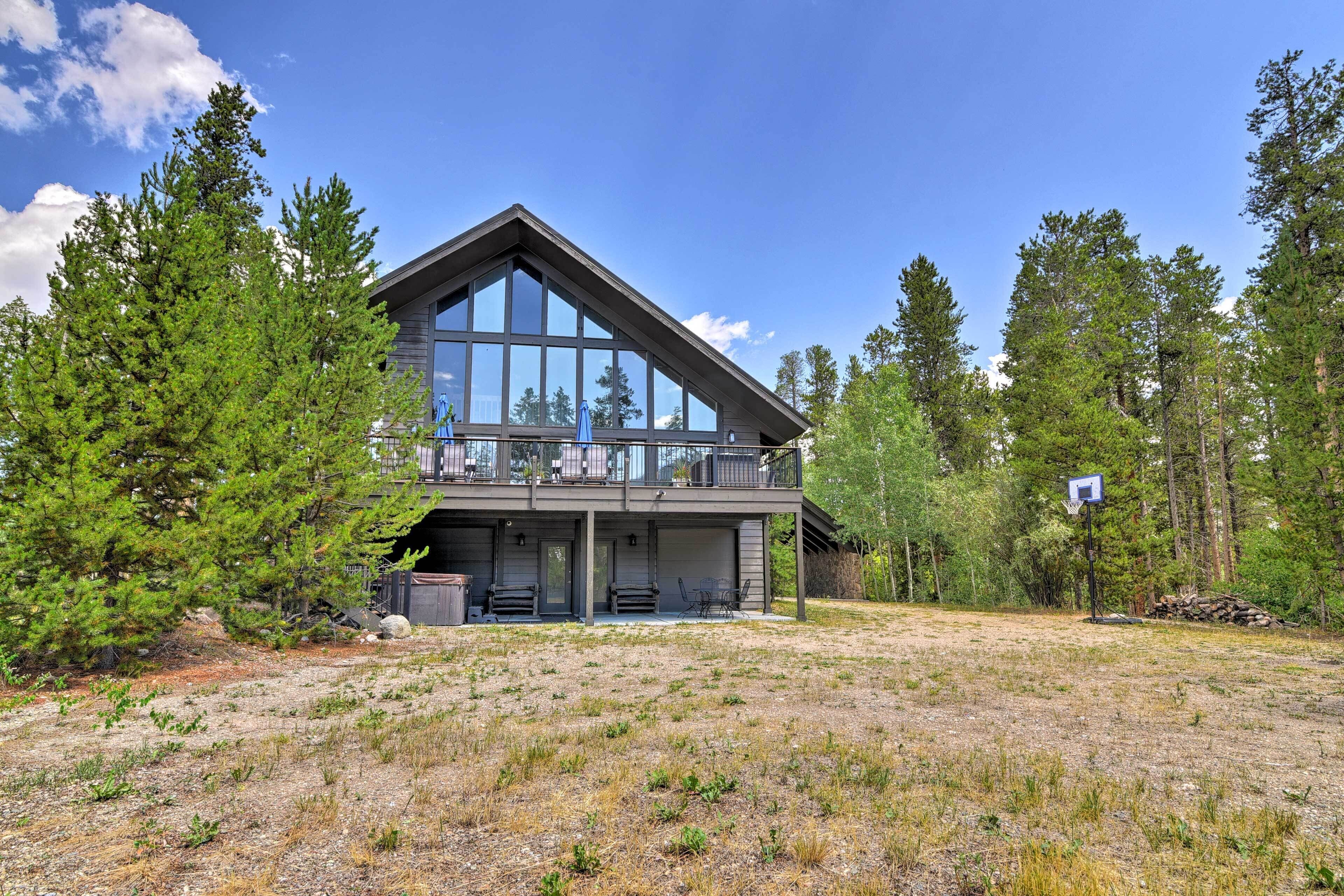 Une maison à deux étages avec un balcon, entourée d’arbres.