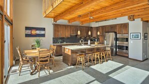 A spacious kitchen with wooden beams, a central island with stools, and modern appliances.