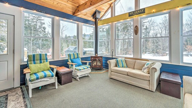 A cozy room with a large window, a wood-burning stove, and a sign reading "Mt. Holly." - Mount Holly Vacation Rental w/ Hot Tub! (Mount Holly)