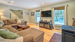 A living room with a sectional sofa, a coffee table, a fireplace, and a large window with curtains. - Mount Holly Vacation Rental w/ Hot Tub! (Mount Holly)