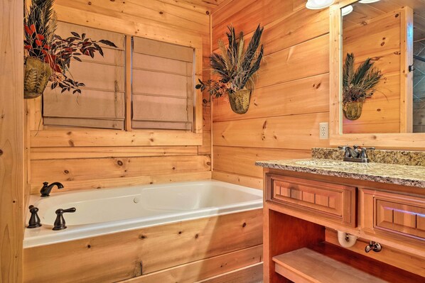 A wooden bathroom with a bathtub, wooden cabinets, and a mirror.