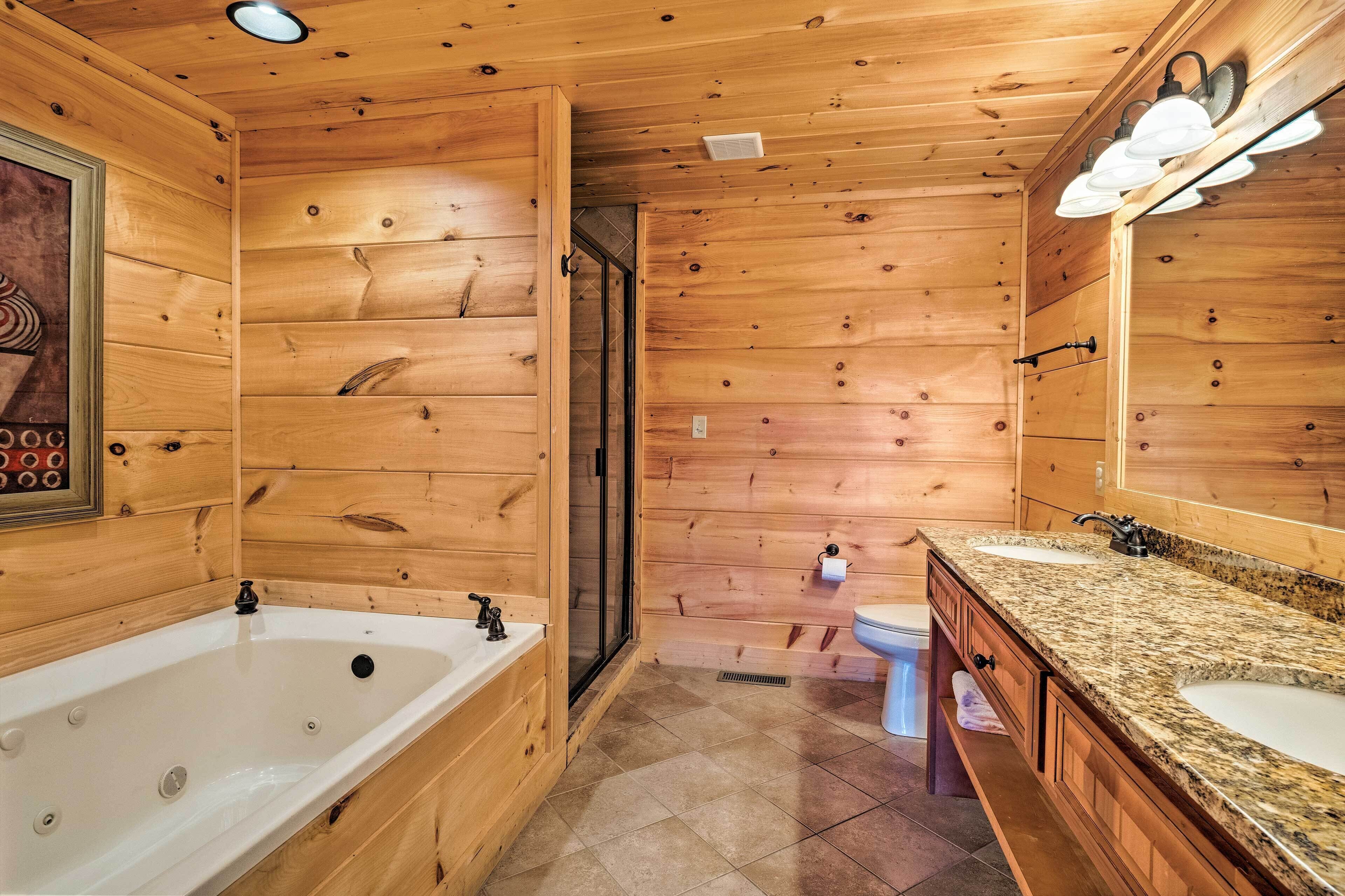 Baño de cabaña de madera con bañera, dos lavabos y ducha.