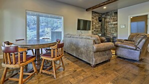 A dining area with a round table and wooden chairs, a grey sofa, and a leather recliner. - Mammoth Creek Apt. Between Bryce Canyon & Zion! (Hatch)