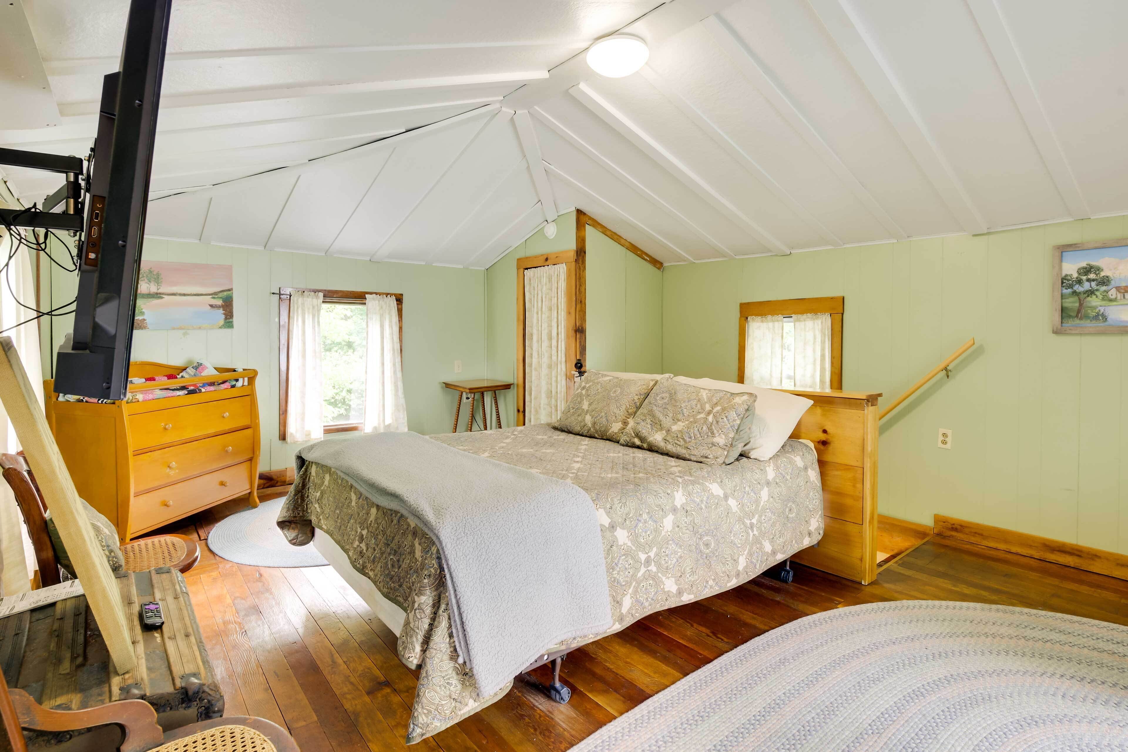 A bedroom with a bed, wooden dresser, and a small table.