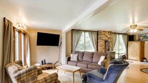 Una sala de estar acogedora con un sofá, un sillón y una mesita de centro. Un televisor de pantalla plana está montado en la pared, y hay una chimenea con chimenea.