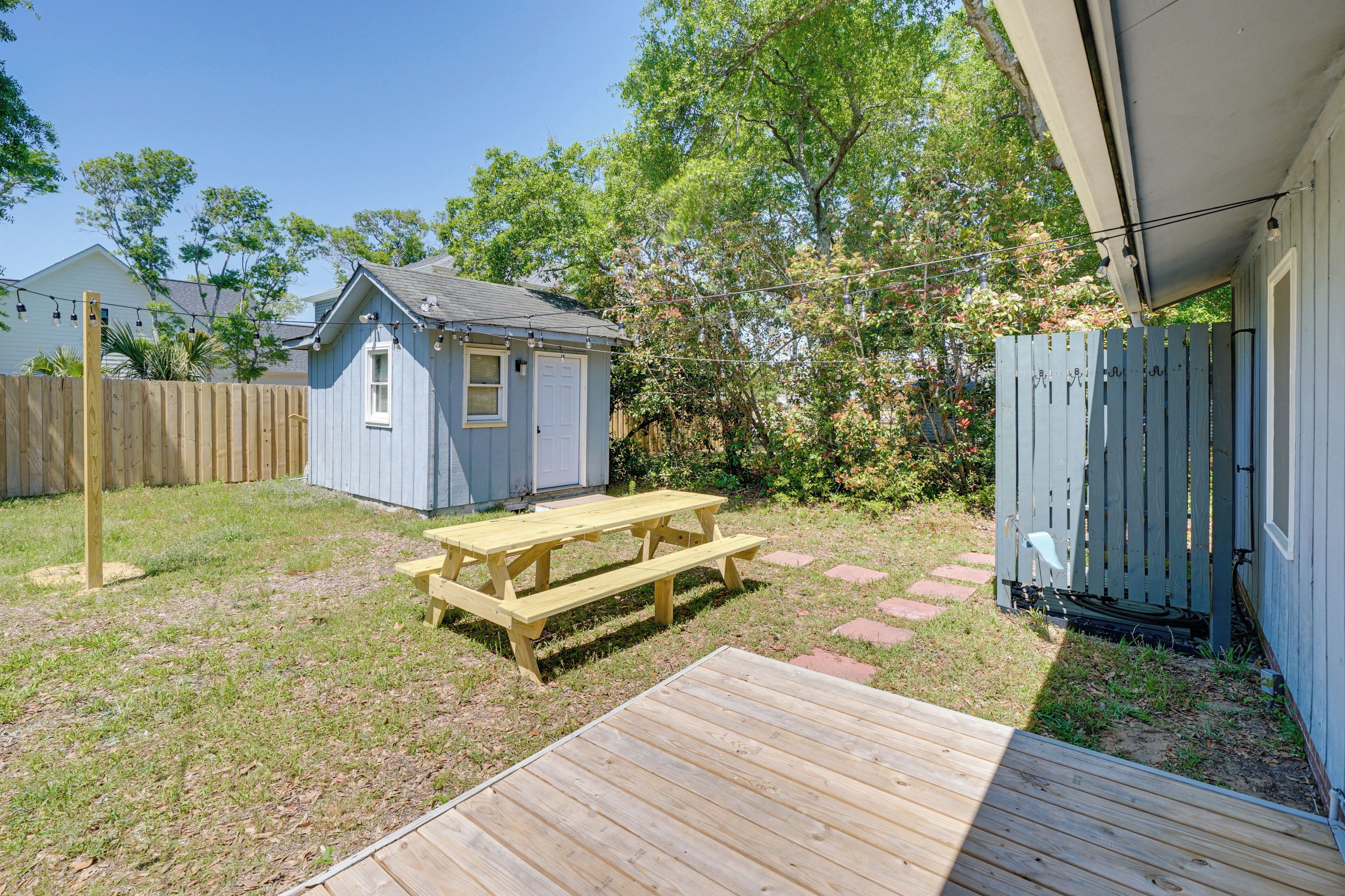 A backyard with a wooden deck, a picnic table, a shed, and a wooden fence.