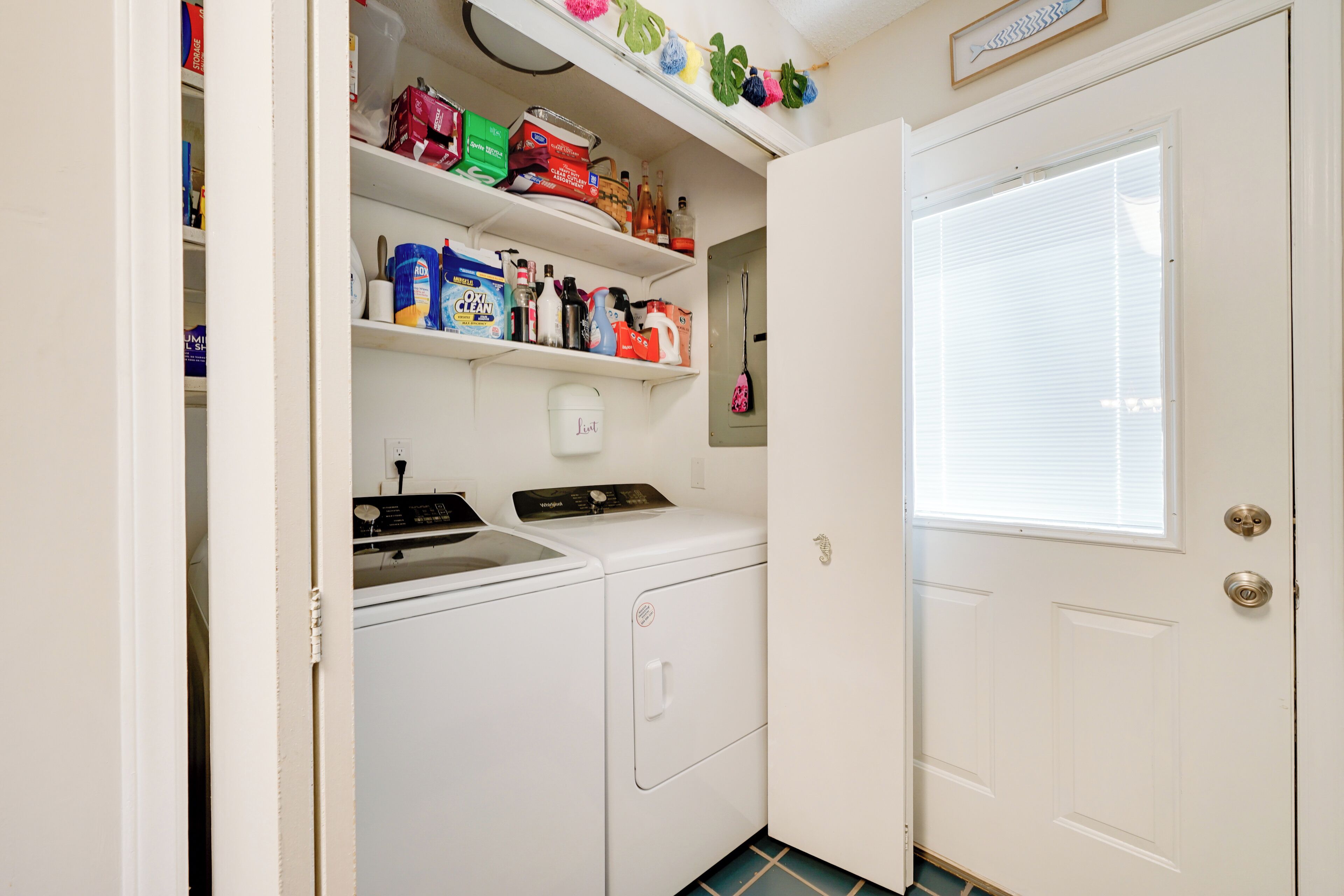A laundry room with a washing machine, dryer, and shelves stocked with cleaning supplies.