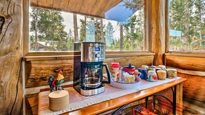 A rustic cabin interior with a wooden table, a coffee maker, and various mugs and cups. - < 1 Mi to Lake Granby: Log Cabin w/ Fire Pit (Grand Lake)