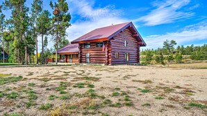 A log cabin with a red roof, surrounded by a grassy field and tall trees. - < 1 Mi to Lake Granby: Log Cabin w/ Fire Pit (Grand Lake)