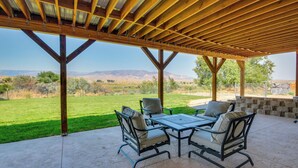 Um terraço ao ar livre com pérgula de madeira, mesa e cadeiras.