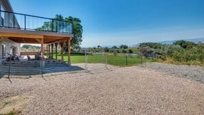 Uma casa moderna com varanda coberta, entrada com calçamento de brita e vista para o campo.