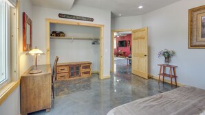 Quarto espaçoso com cômoda de madeira, luminária, ventilador de teto e uma placa na parede.