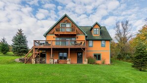 A two-story log cabin with a balcony, stone steps, and a stone wall entrance. - Mountaintop Ellicottville Home: 7 Mi to Ski Resort (Ellicottville)