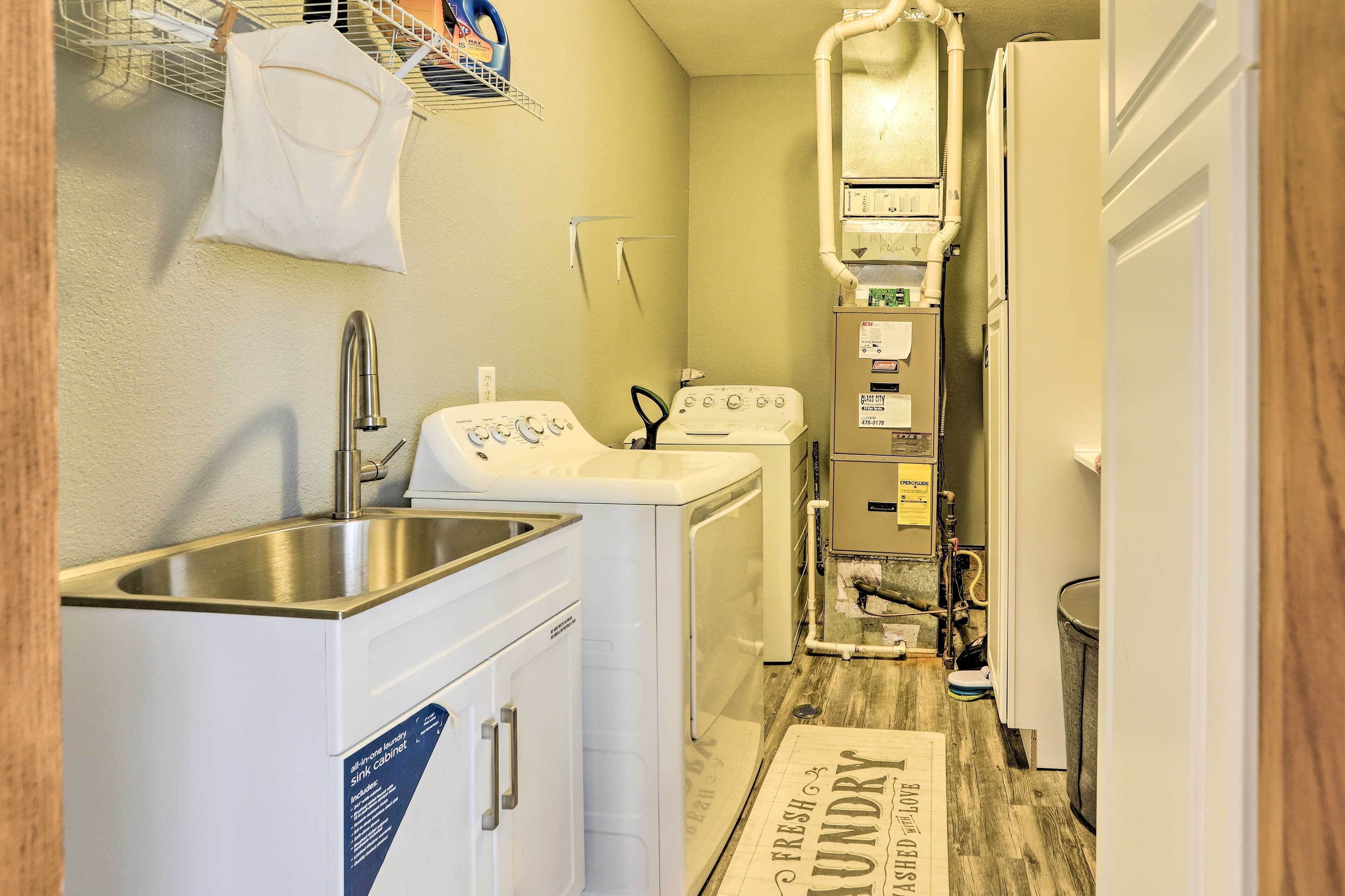 A compact laundry room with a sink, washing machine, and dryer.