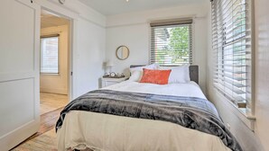A bedroom with a bed, a nightstand, a ceiling fan, and a window with blinds.