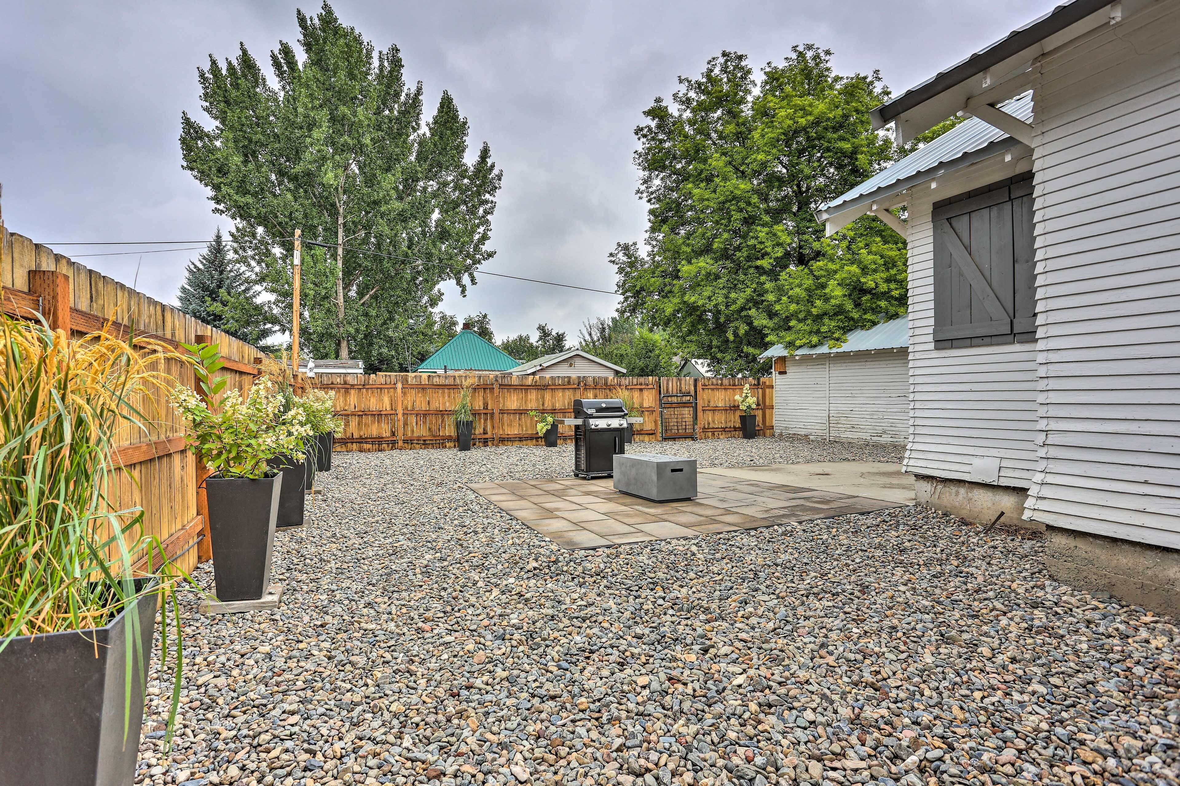 A backyard with a wooden fence, a barbecue grill, and a shed.