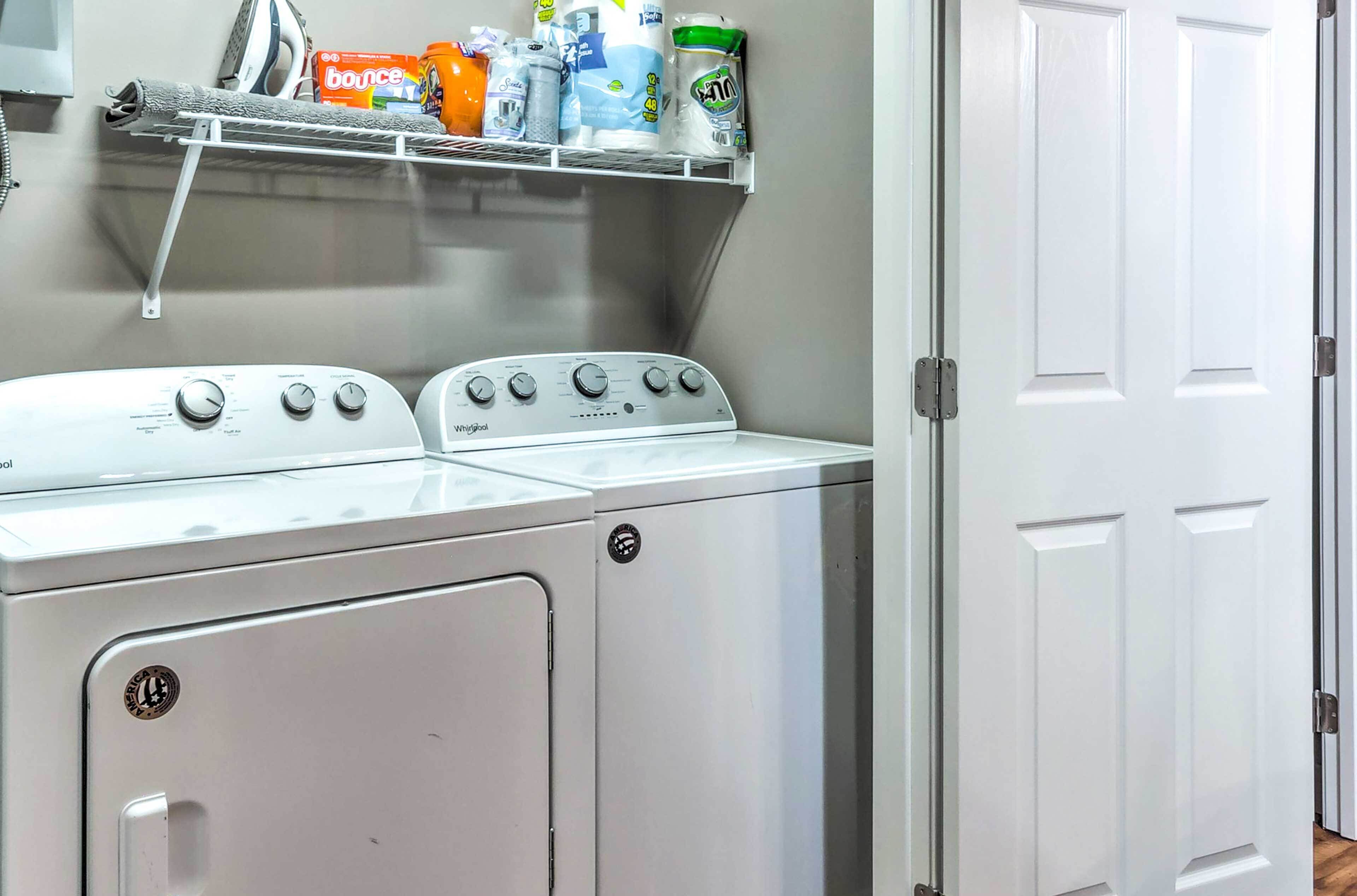 A laundry area with a washing machine and dryer, a shelf with laundry supplies, and a white door.