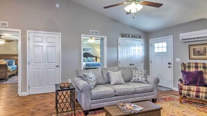 A living room with a grey sofa, a coffee table, a patterned rug, and a plaid armchair. - Pet-friendly Brownsville Retreat w/ Porch! (Brownsville)