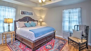 A bedroom with a wooden bed, two bedside lamps, a chair, and a ceiling fan. - Pet-friendly Brownsville Retreat w/ Porch! (Brownsville)