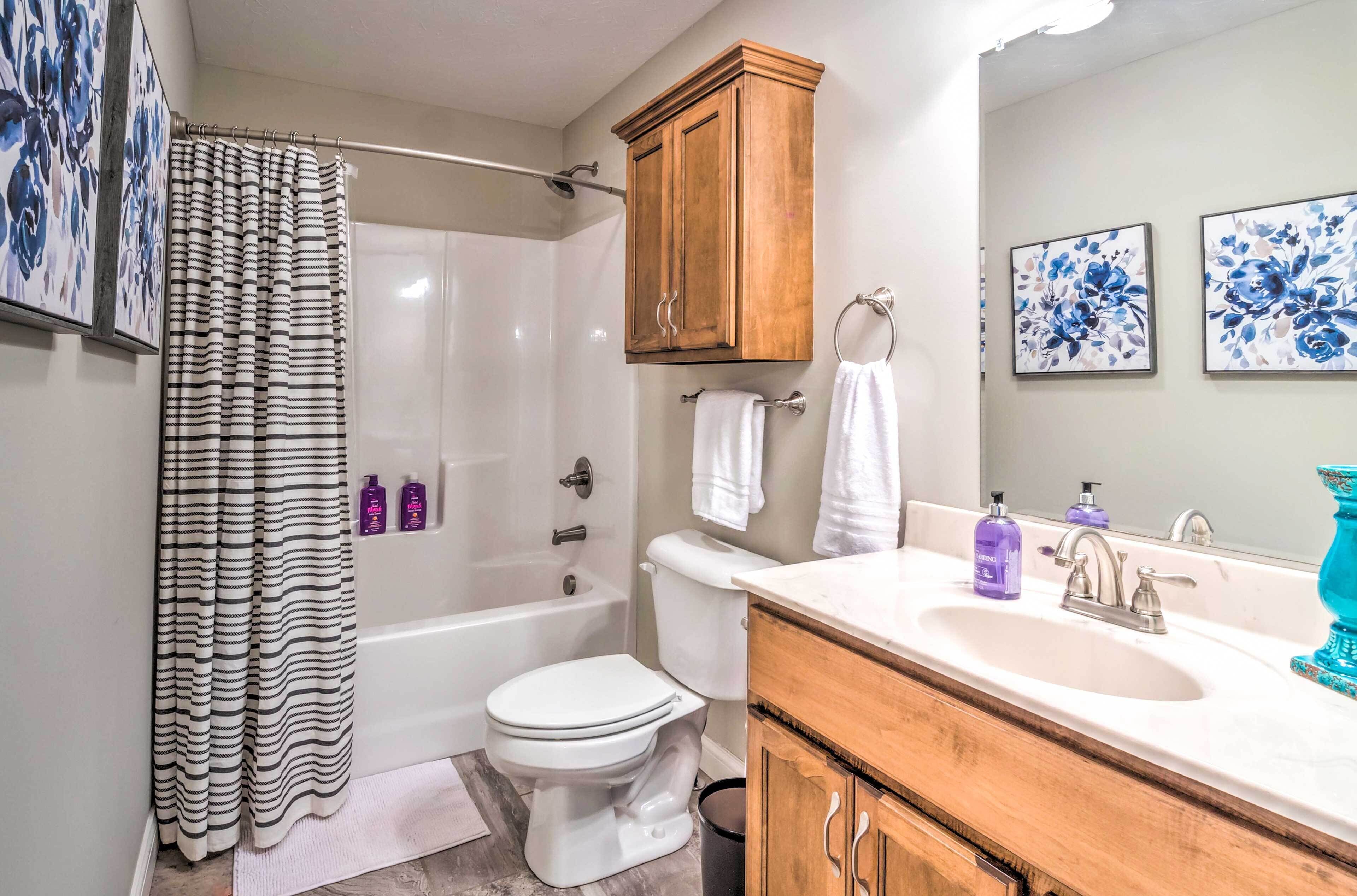A bathroom with a shower, toilet, sink, and wooden cabinets.