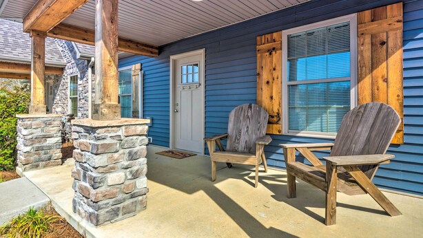 A covered porch with stone pillars, wooden chairs, and a stone fireplace. - Pet-friendly Brownsville Retreat w/ Porch! (Brownsville)