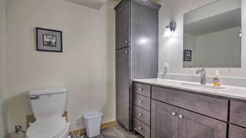 A bathroom with a toilet, a sink with a mirror, and a cabinet.