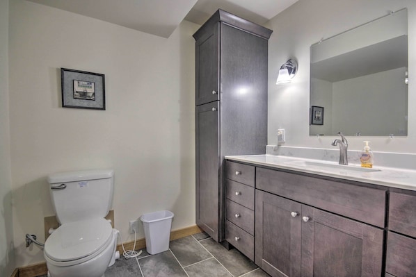 A bathroom with a toilet, a sink with a mirror, and a cabinet.