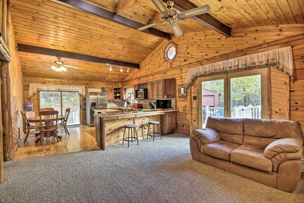 A log cabin interior with a kitchen, dining area, and living room.