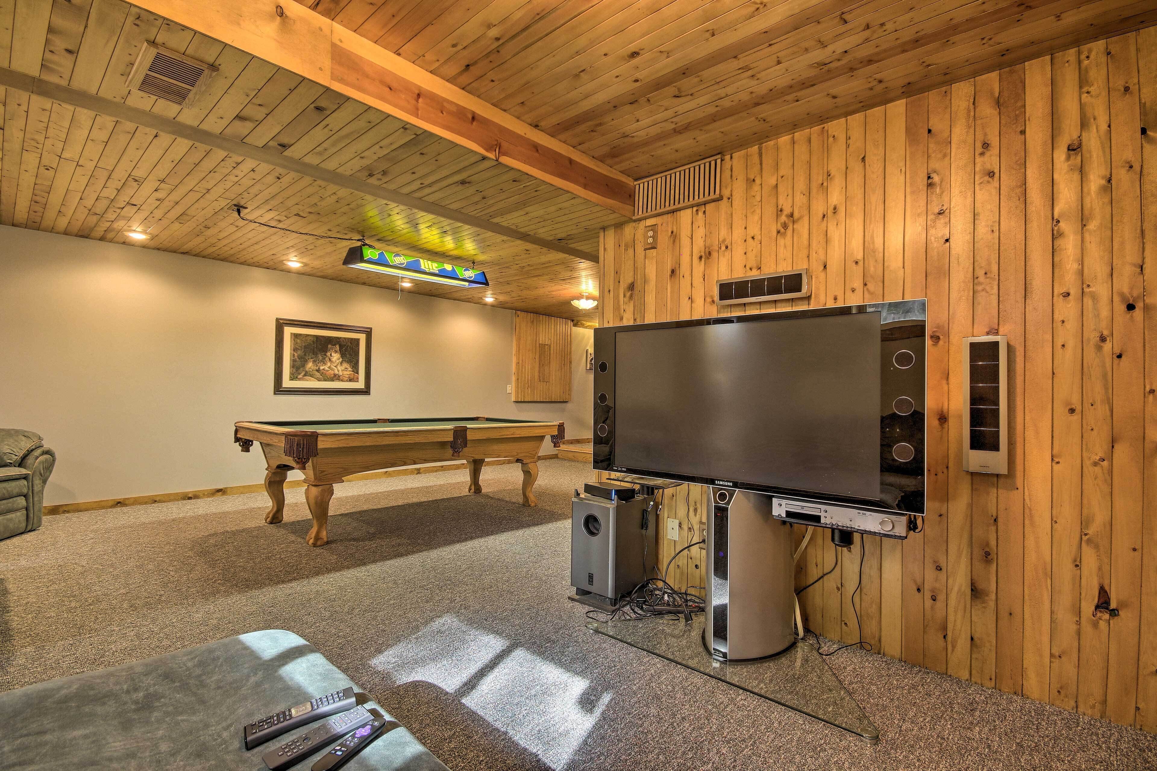 A room with a pool table, a large flat-screen TV, and a sound system.