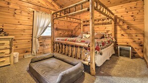 Un dormitorio de cabaña de madera con una cama con dosel, una mesita de noche pequeña y un calentador.