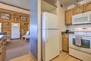 A kitchen with wooden cabinets, a white refrigerator, a microwave, and a stove. - Pioche Family Cabin w/ View - Walk to Main St! (Pioche)
