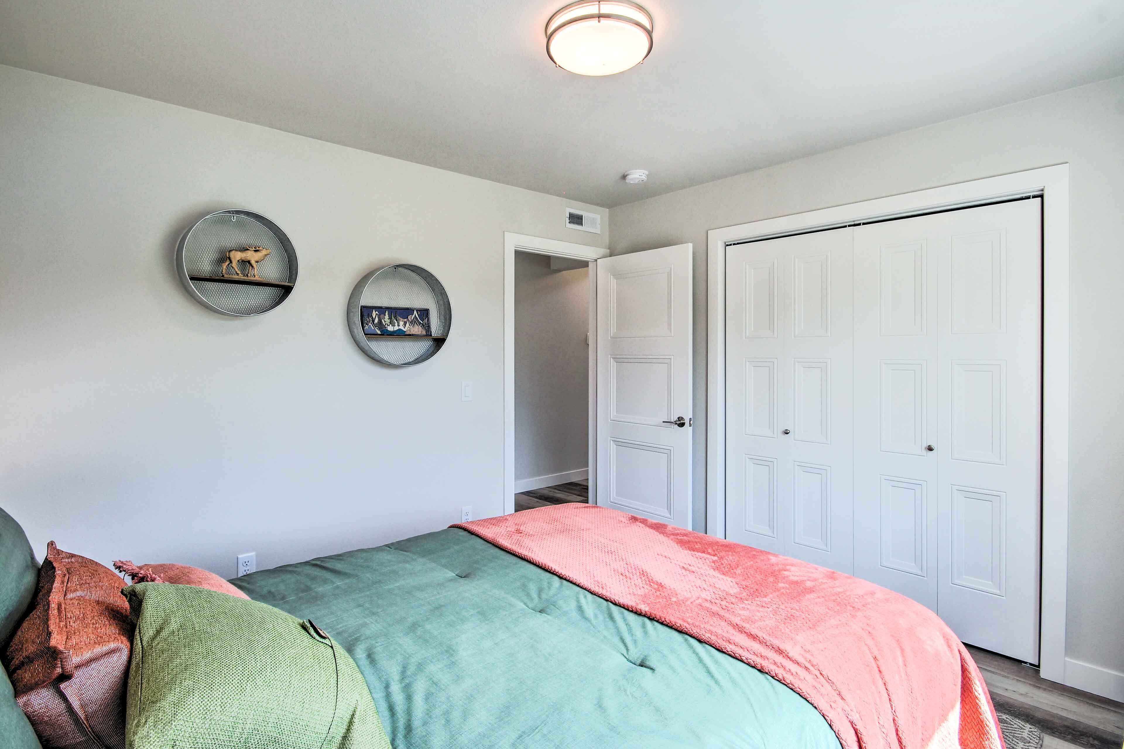 A bedroom with a bed, a closet, and a door to another room.