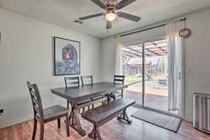 A dining area with a table, chairs, and a bench. There is a ceiling fan, a framed picture on the wall, and a view of the backyard through a glass door. - Relaxing Redmond Retreat: Golf, Hike & Ski! (Redmond)