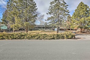A two-story house with a front yard, surrounded by tall evergreen trees. - Relaxing Redmond Retreat: Golf, Hike & Ski! (Redmond)