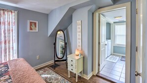 Une chambre à coucher comprenant un lit, une commode, un miroir, un tapis et une porte donnant sur une autre pièce.