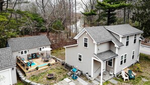 Une maison à deux étages dotée d’une terrasse, d’un espace salon extérieur et d’un barbecue.