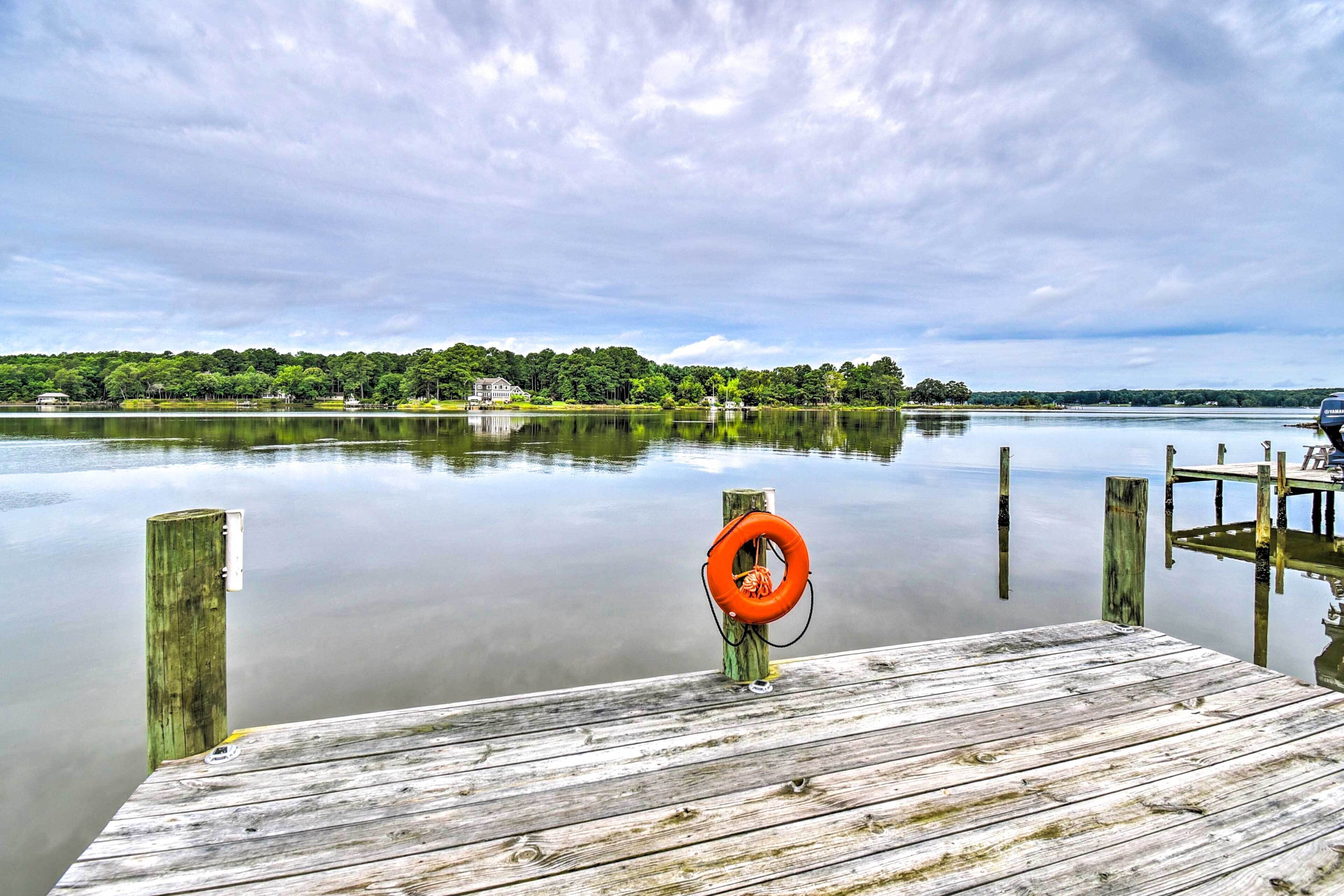 A wooden dock extending into calm water with a lifebuoy on the end.