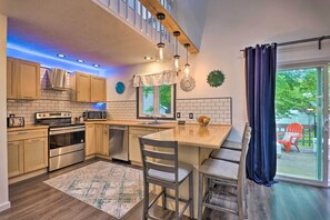 A modern kitchen with wooden cabinets, stainless steel appliances, a central island with bar stools, and a view of the outdoors. - 7 Mi to Tobyhanna State Park: Quiet Retreat! (Tobyhanna)