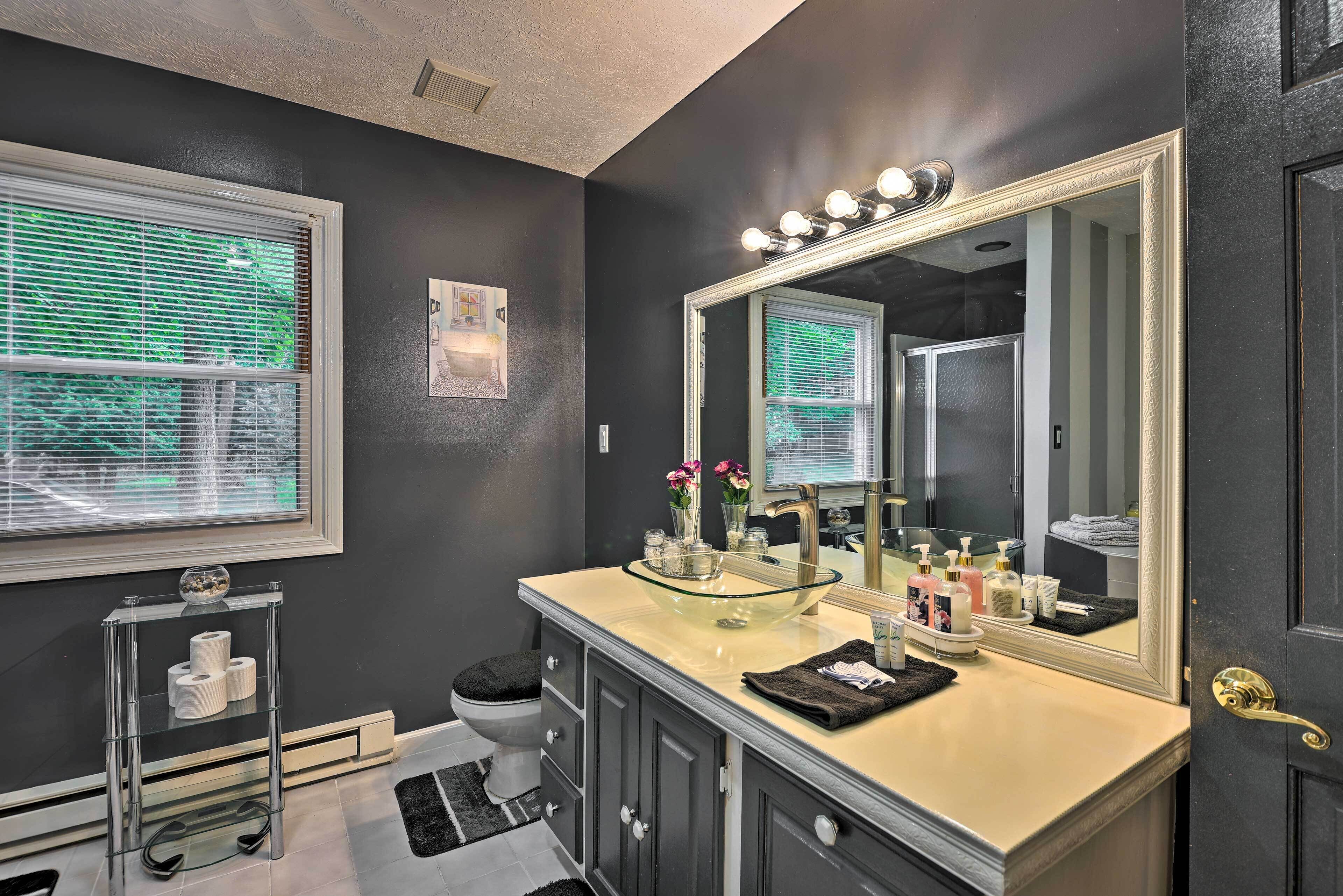 A bathroom with a large mirror, vanity, and a toilet.