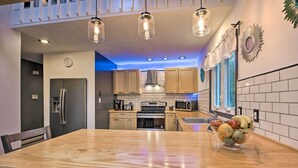 A modern kitchen with wooden cabinets, stainless steel appliances, and a central island with a fruit bowl.