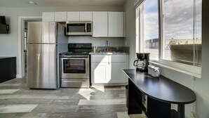 Eine moderne Küche mit Edelstahlgeräten, weißen Schränken und einem großen Fenster für natürliches Licht.