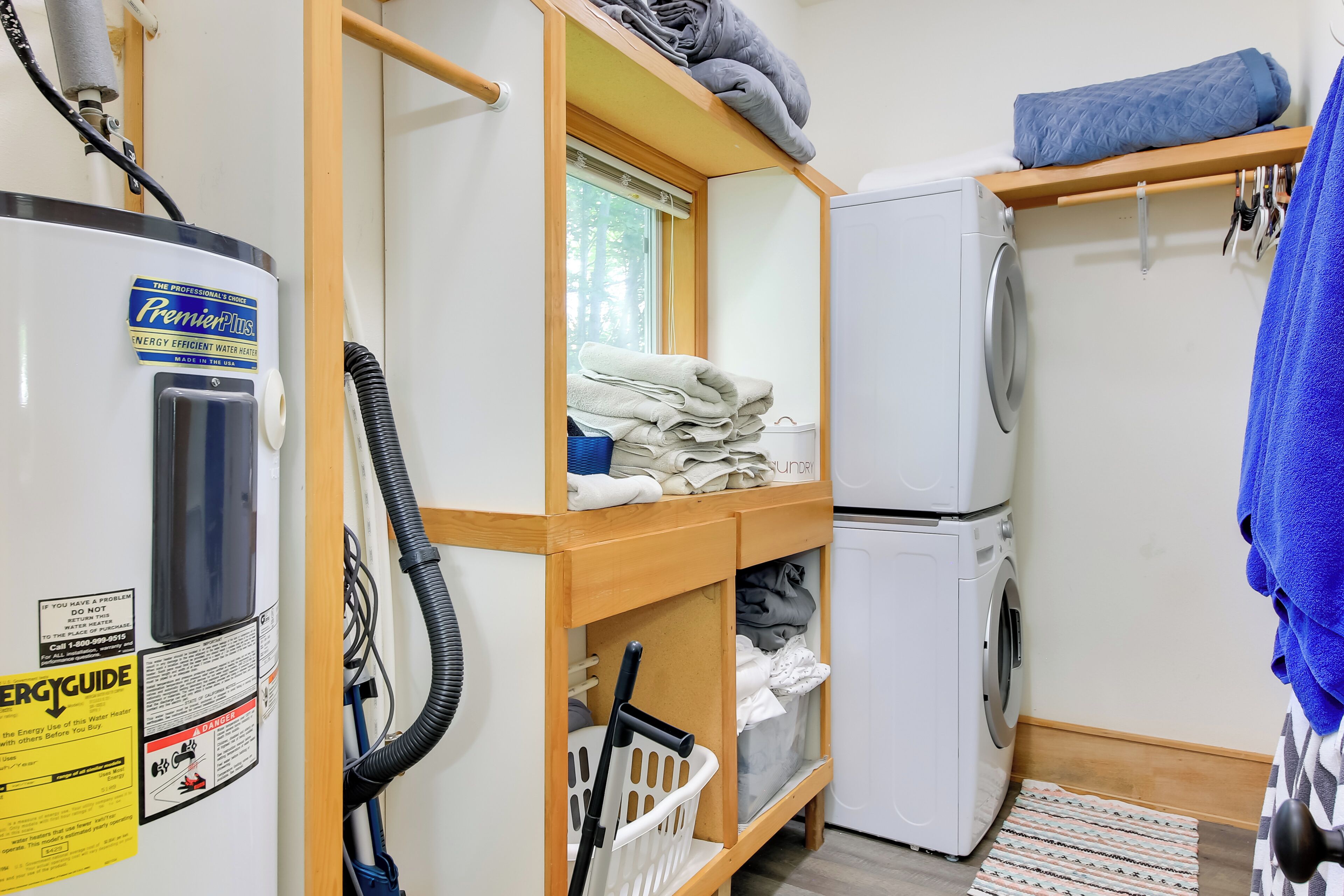 Een kleine badkamer met een boiler, een wasmachine en een droogrek.