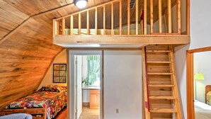 A loft bedroom with a wooden ceiling, a bunk bed, a wooden staircase, and a view of the kitchen. - Rustic Taswell Cabin: Grill + Walk to Patoka Lake! (Taswell)
