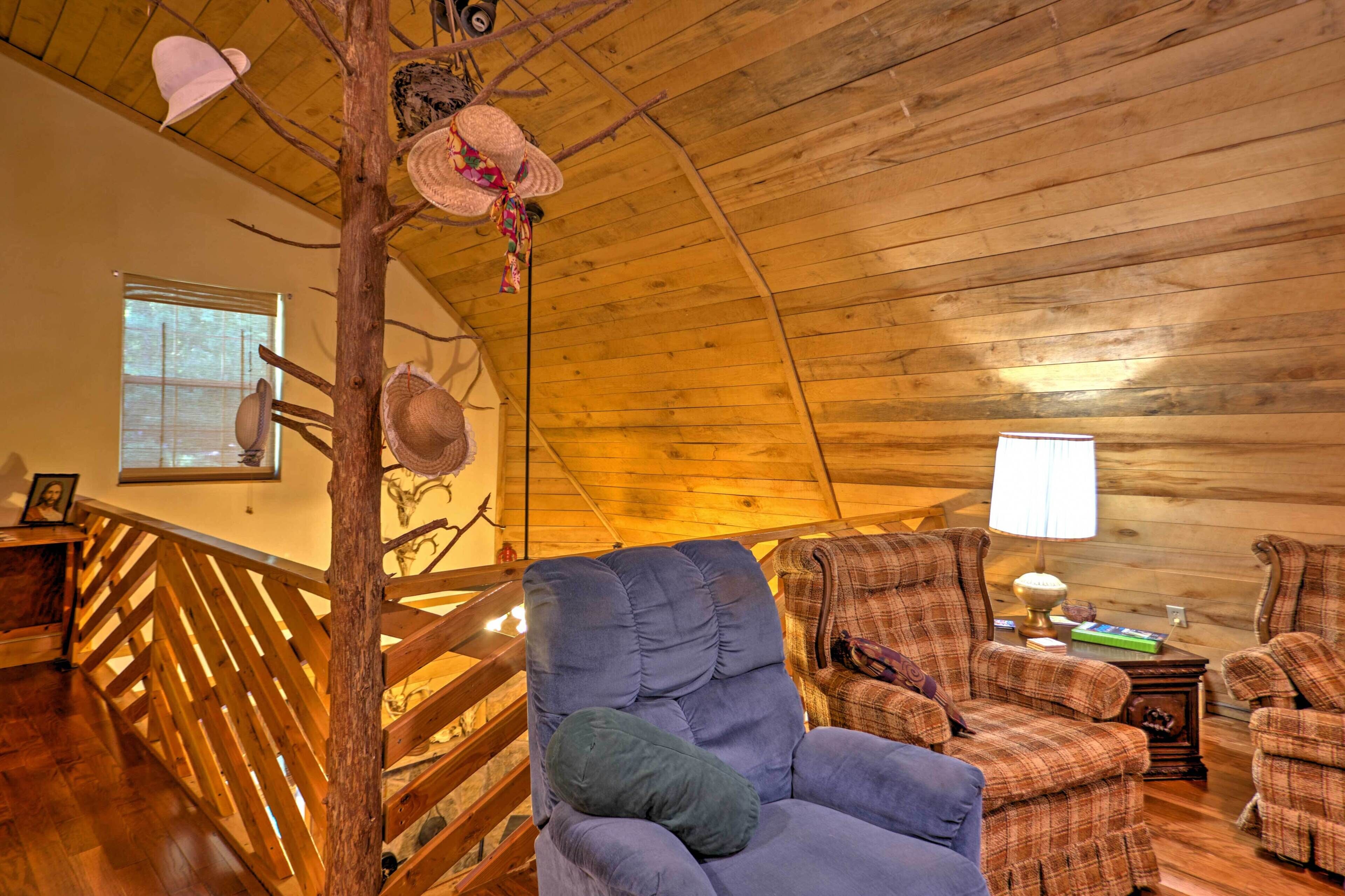 A cozy cabin interior with a wooden ceiling, a wooden staircase, and plaid furniture.