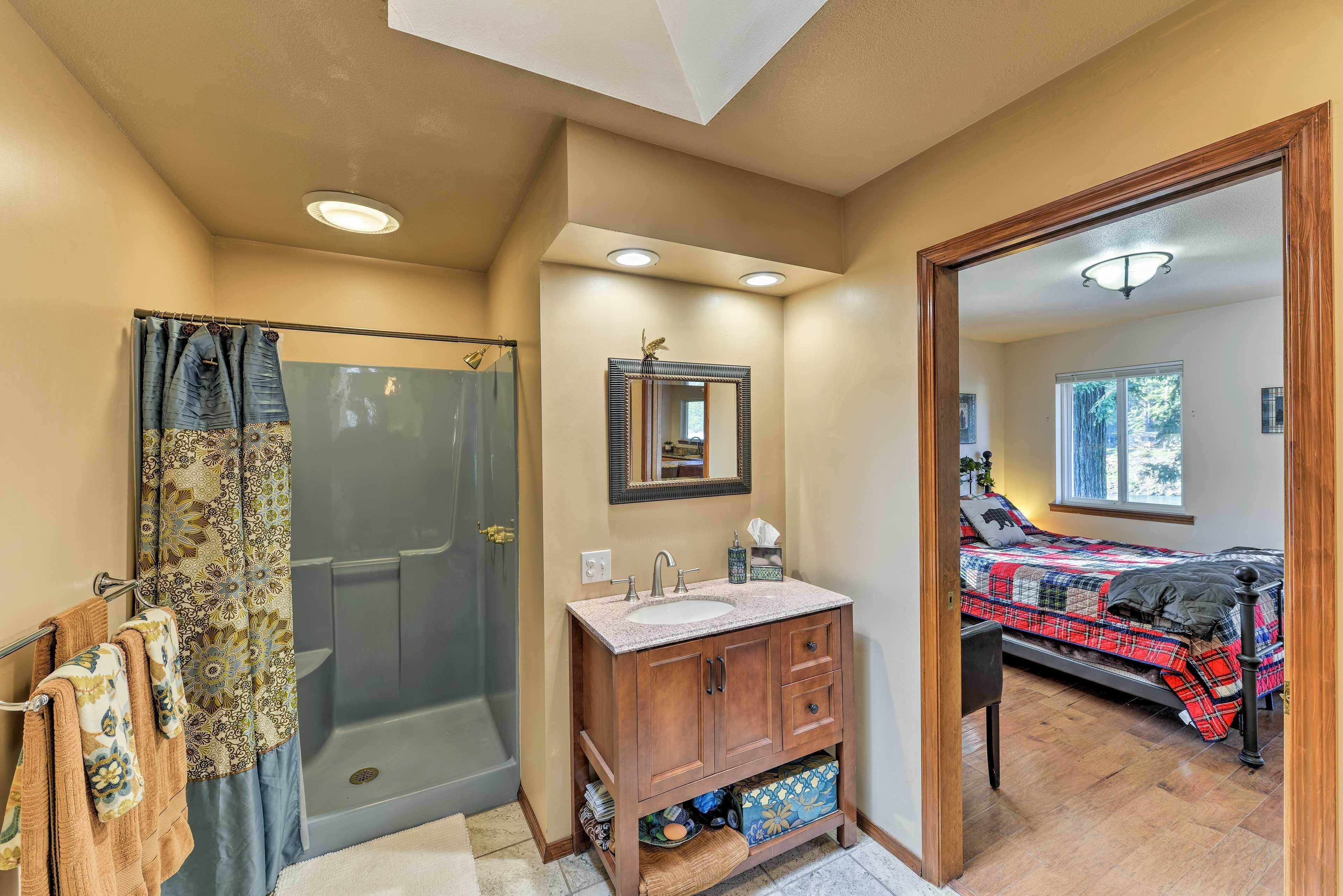A bathroom with a shower, sink, and mirror.