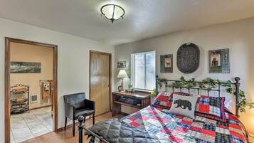 A bedroom with a bed, a desk, a chair, and a window.