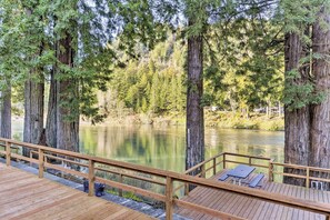 A wooden deck with benches overlooking a calm lake surrounded by tall trees. - Riverfront Crescent City Home, 8 Mi to Beach! (Crescent City)